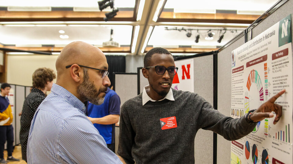 Poster presenter defining poster to attendee at UNL Microbiology Research Symposium
