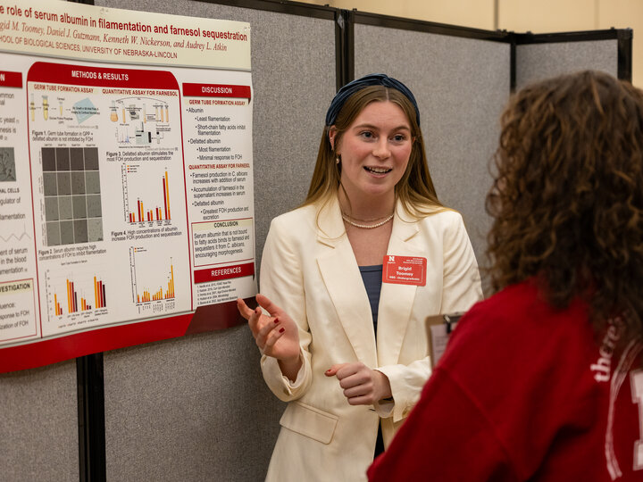 Symposium participant presenting poster to peer